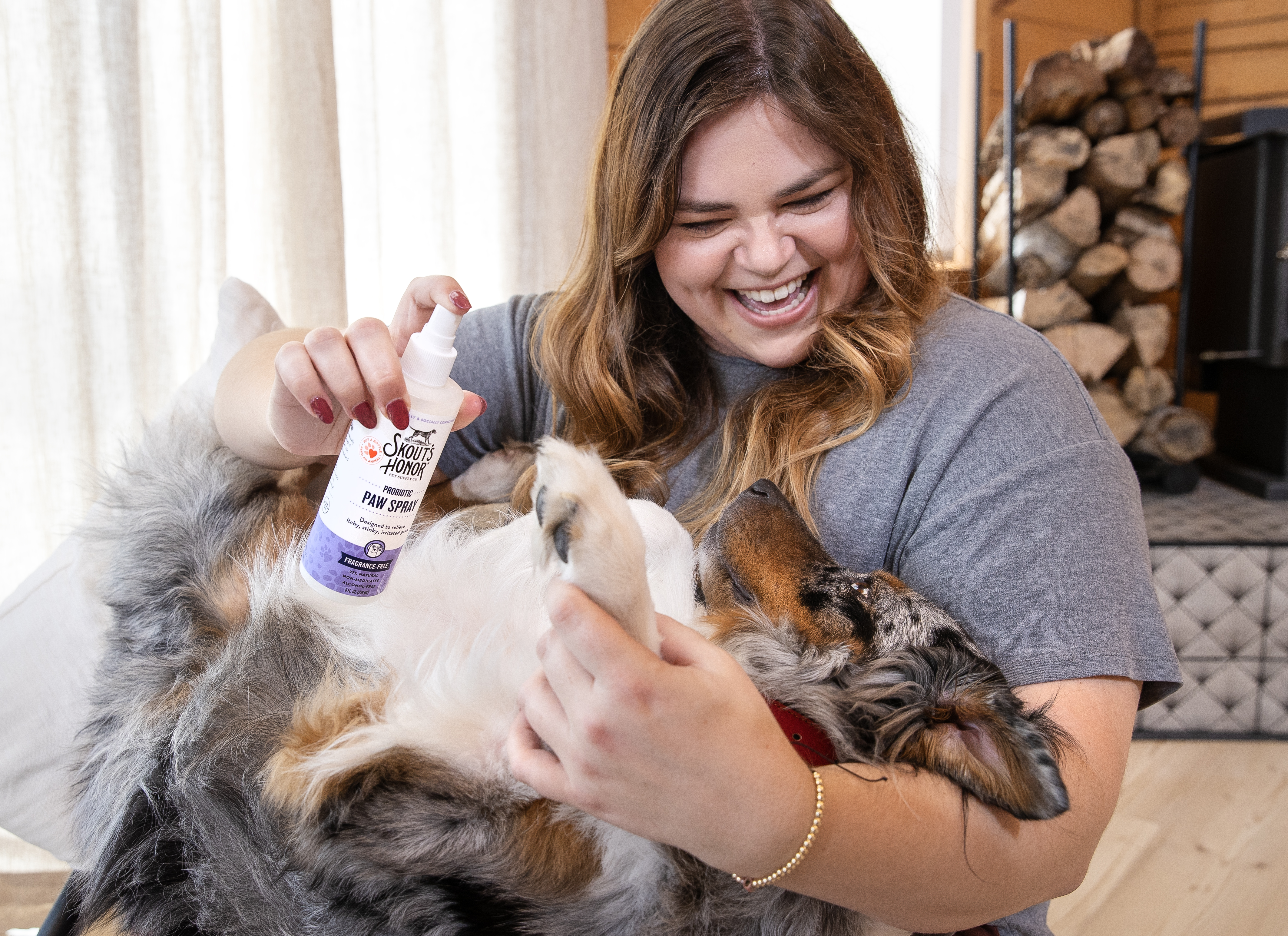 a woman using skout's honor paw spray on an australian shepherd